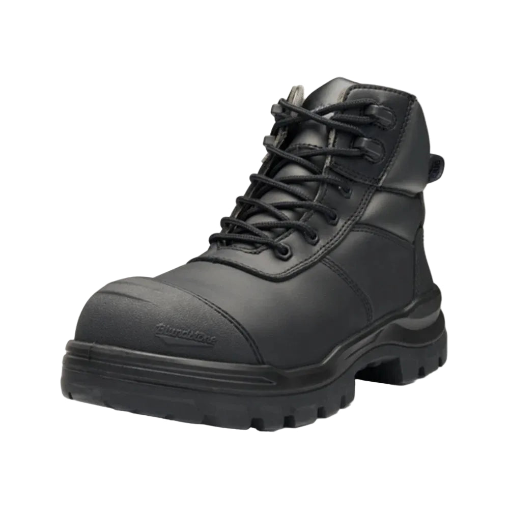 A black high-top safety work boot with a protective toe cap, black laces, and a rugged sole, shown against a light beige background.